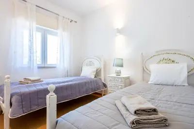 a white bedroom with two beds and a window at Sea Blue Apartment - Luz Ocean Club in Luz