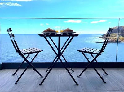 a table and two chairs on a balcony with the ocean at Ocean Cliff Apartment in Santa Cruz