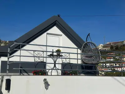 a picnic table with an umbrella and benches at Isabela House in Ponta do Sol