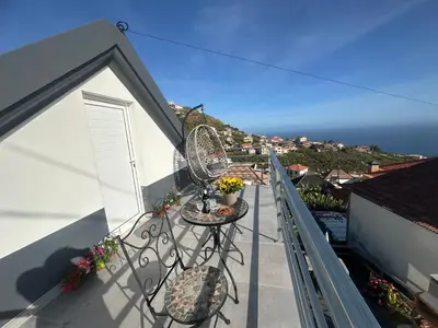 a white house with a hill in the background at Isabela House in Ponta do Sol