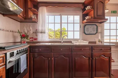 a kitchen with wooden cabinets and a sink and a window at Sunset House in Arco da Calheta