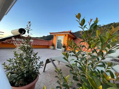 a patio with a bench and plants and a house at Sunset House in Arco da Calheta