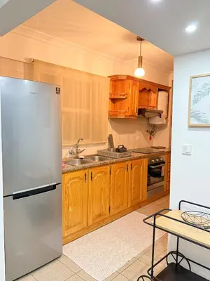 a kitchen with wooden cabinets and a stainless steel refrigerator at The Palms Apartment - Sun & Sea Madeira in Madalena do Mar