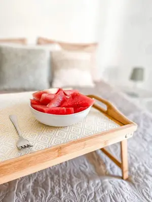 a bowl of watermelon on a table on a bed at The Palms Apartment - Sun & Sea Madeira in Madalena do Mar