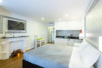 a white bedroom with a bed and a kitchen at Le Vingale in Funchal