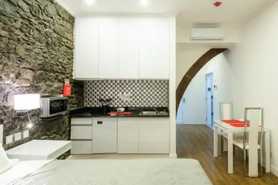 a kitchen with white cabinets and a stone wall at Le Vingale in Funchal
