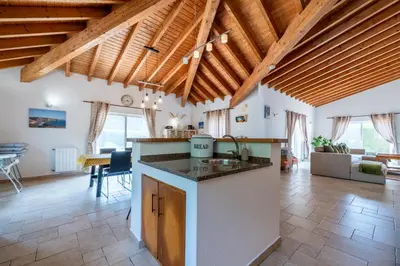 an open kitchen and living room with wooden ceilings at Casa Garrod - Spacious Family Villa in Aljezur