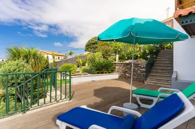 a patio with two chairs and an umbrella at Villa Dinis by Holiday Rental Madeira in Calheta