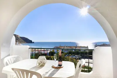 a white table with a bottle of wine on a balcony at 3B Waterside in Luz
