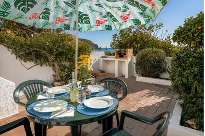 a table with chairs and an umbrella on a patio at 3B Waterside in Luz