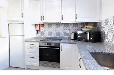 a kitchen with white cabinets and a black oven at 3B Waterside in Luz
