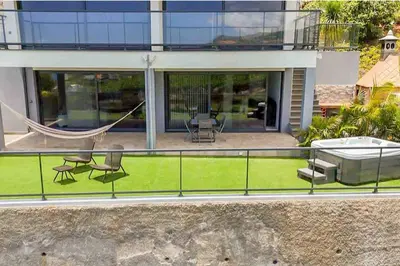 a balcony of a house with a hammock at House - sleeps 3 free parking garden & jacuzzi in Estreito da Calheta