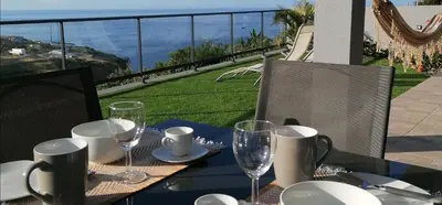 a table with wine glasses on a balcony with a view at House - sleeps 3 free parking garden & jacuzzi in Estreito da Calheta
