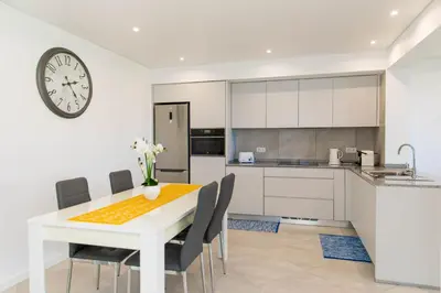 a kitchen with a table and chairs and a clock at House - sleeps 3 free parking garden & jacuzzi in Estreito da Calheta