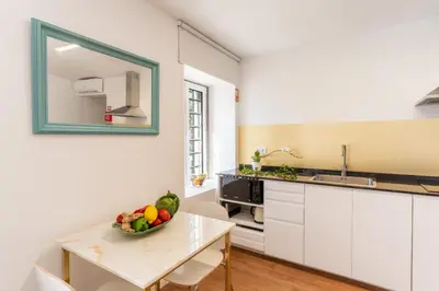 a kitchen with white cabinets and a table with a bowl of fruit at Casa Amarela Apartments - by Casas na Ilha in Câmara de Lobos