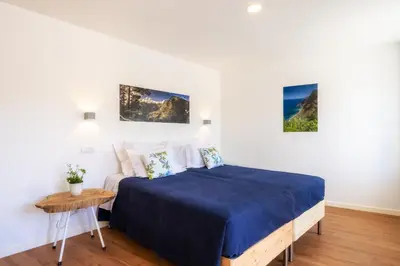 a bedroom with a bed with blue sheets and a table at Casa Amarela Apartments - by Casas na Ilha in Câmara de Lobos