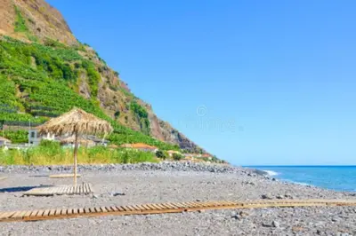 a beach with a straw umbrella and the ocean at Casa AIDA SEA VIEW in Relógio do Poiso