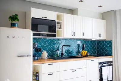 a kitchen with white cabinets and a blue tile back splash at Rooftop Funchal II by Madeira Best Apartments in Funchal