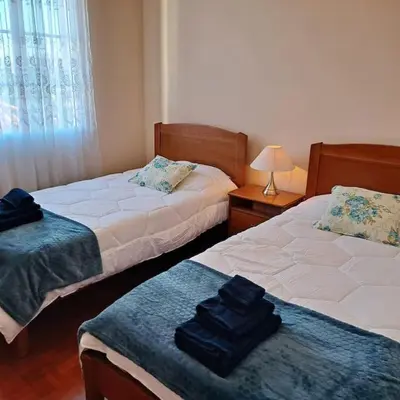 a bedroom with two beds and a table with a lamp at Chalé Funchal - City view in Funchal