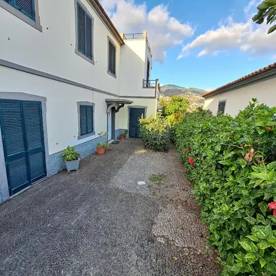 a driveway leading to a white building with blue doors at Chalé Funchal - City view in Funchal