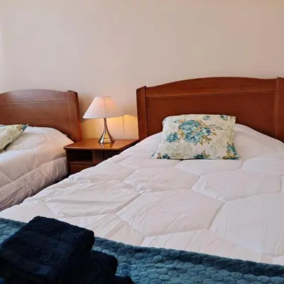 a white bed with a pillow and a lamp on a table at Chalé Funchal - City view in Funchal