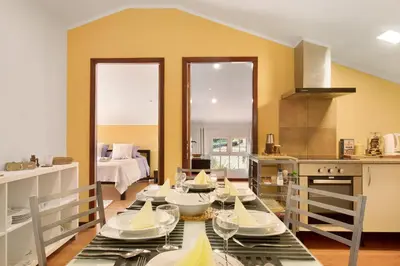 a dining room with a table and a kitchen at Casa Amarela in Caniço