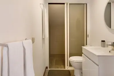 a white bathroom with a toilet and a sink at Casa Amarela in Caniço