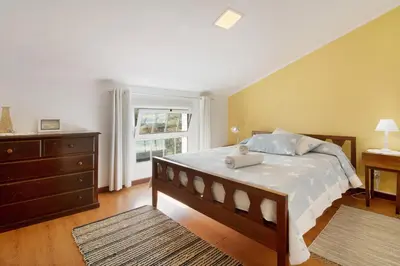 a bedroom with a bed and a dresser and a window at Casa Amarela in Caniço