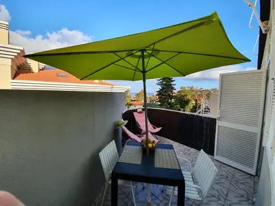 a table with a green umbrella on a balcony at Apartamentos Navio Azul in Funchal