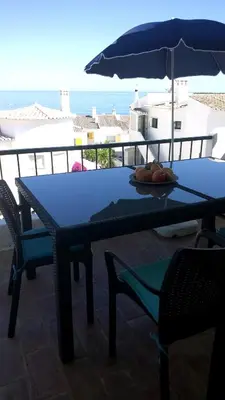 a blue table with chairs and an umbrella on a balcony at Casa Vista Mar in Luz