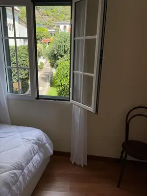 a bedroom with a window and a bed and a chair at Cosy 2 bedroom home in the heart of Jardim do Mar in Jardim do Mar