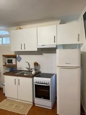 a kitchen with white cabinets and a stove and refrigerator at Cosy 2 bedroom home in the heart of Jardim do Mar in Jardim do Mar