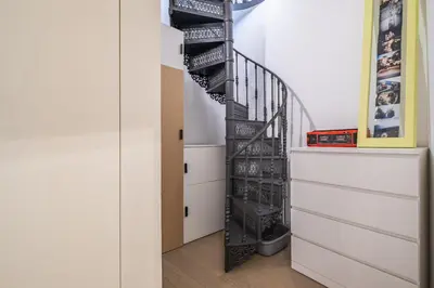 a black spiral staircase in a room with white drawers at Casa do Luar - By WeHost in Funchal