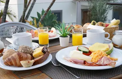 a table with plates of breakfast foods and orange juice at Vila Camacho Guest House in Funchal