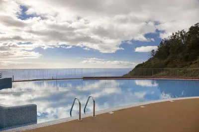 a large swimming pool with a view of the water at Village Cabo Girao in Câmara de Lobos