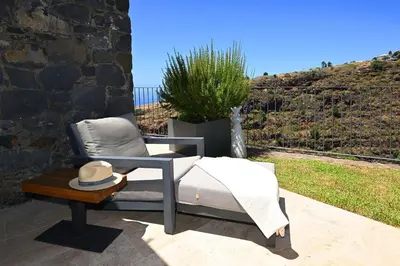 a chair with a hat sitting on a patio at The Rock Villas in Estreito da Calheta