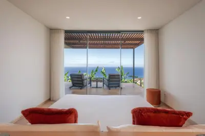 a bedroom with a bed and a view of the ocean at The Rock Villas in Estreito da Calheta