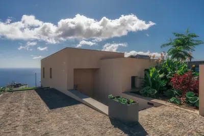 a house on the beach with the ocean in the background at The Rock Villas in Estreito da Calheta