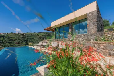 a house with a swimming pool next to a mountain at The Rock Villas in Estreito da Calheta