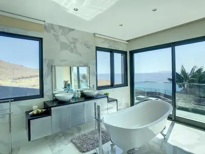 a bathroom with a tub and two sinks and windows at Villa Bahari by LovelyStay in Caniçal