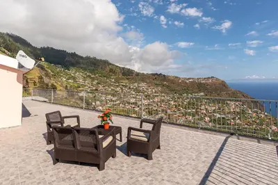 a balcony with chairs and a table and a view of the ocean at Casa Raimunda, Big apartment with amazing views in Arco da Calheta