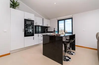 a kitchen with white cabinets and a black counter top at Casa Raimunda, Big apartment with amazing views in Arco da Calheta