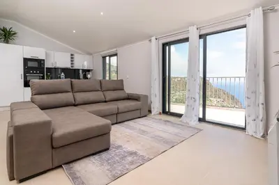 a living room with a couch and large windows at Casa Raimunda, Big apartment with amazing views in Arco da Calheta
