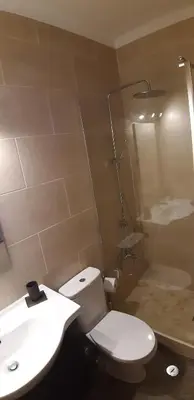 a bathroom with a white toilet and a sink at Queen Palm in Luz