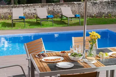 a wooden table with food on it next to a pool at The Yellow House by LovelyStay in Funchal