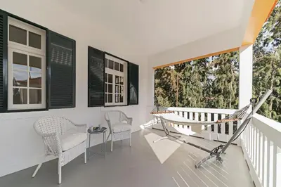 a porch with a swing and chairs on a balcony at The Yellow House by LovelyStay in Funchal