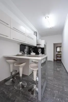 a kitchen with white cabinets and bar stools at City View Apartment by Homie in Funchal