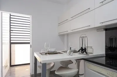 a kitchen with white cabinets and a white table at City View Apartment by Homie in Funchal