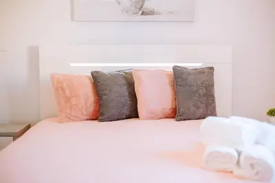 a white bed with pink and grey pillows at Olinda's Place by Amazing Madeira in Boaventura