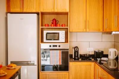 a kitchen with wooden cabinets and a white microwave at Olinda's Place by Amazing Madeira in Boaventura